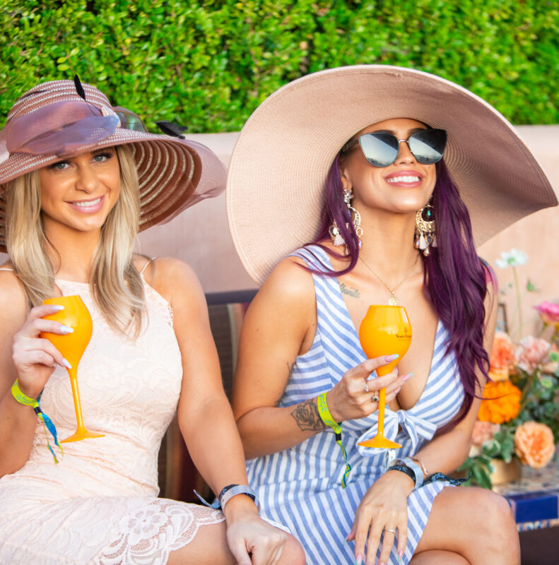 two women in hats drinking champagne on outdoor patio