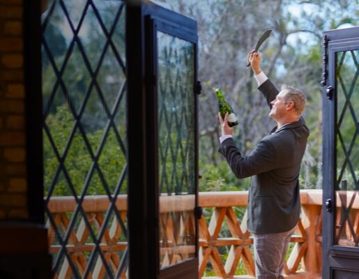 Opening champagne on patio with knife