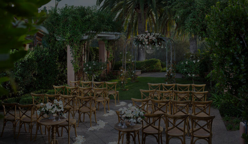 Rose garden set for small wedding ceremony with wood chairs and florals
