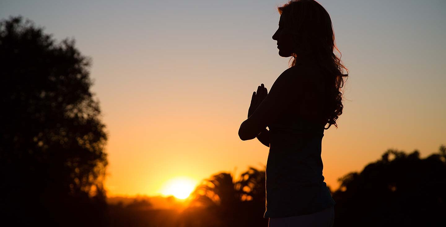 silhouette of woman doing yoga at sunset