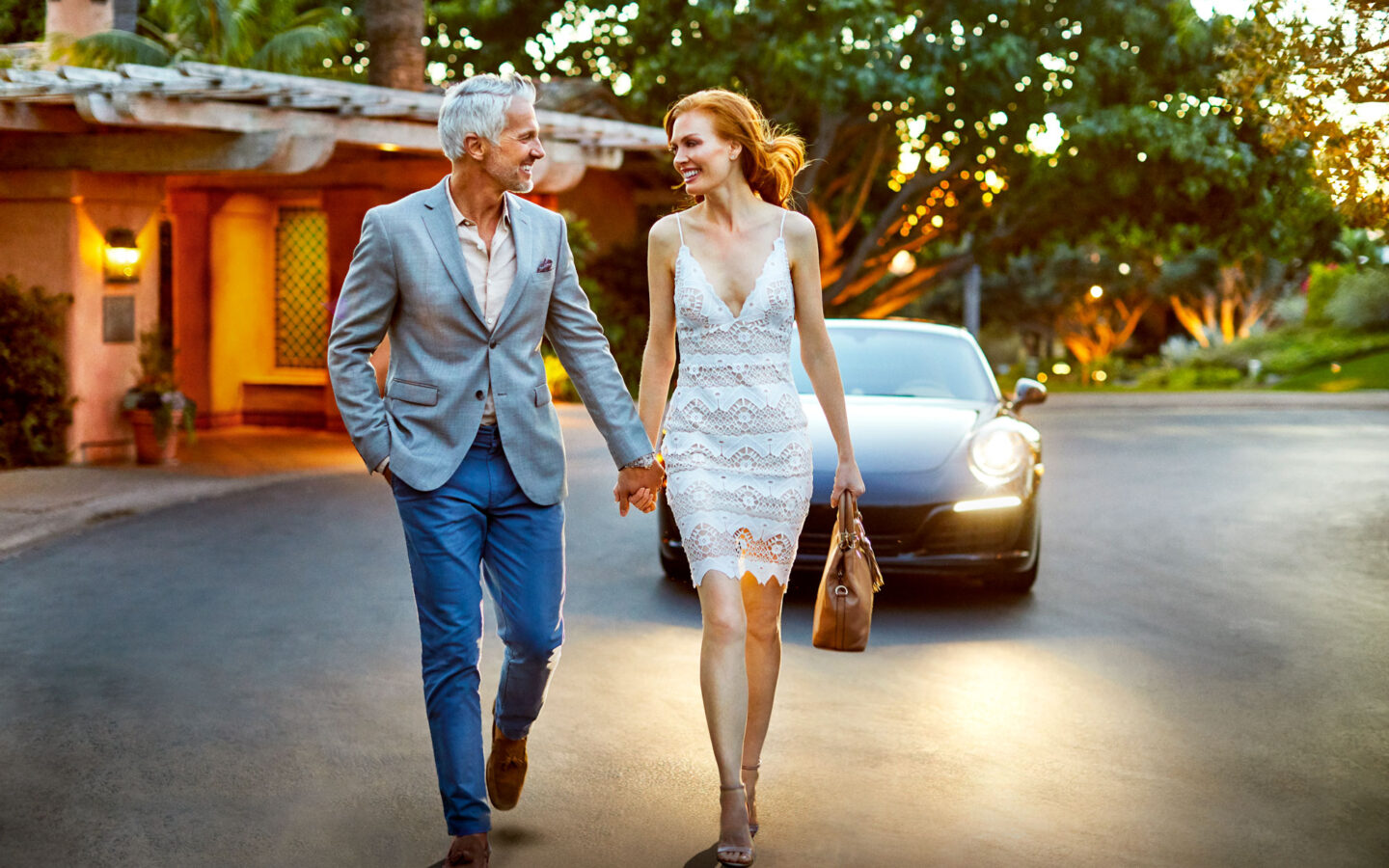 Elegantly dressed man and woman walking hand in hand down the hotel entryway