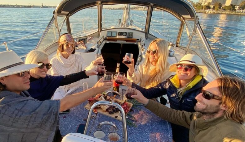 6 people on a boat around a table with wine and food