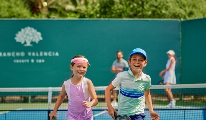 Two children running on the pickleball court