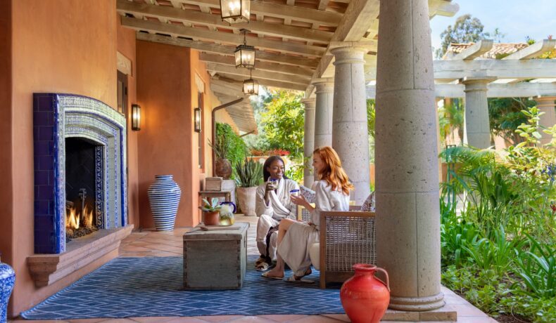 two women sitting by Spa outdoor fireplace