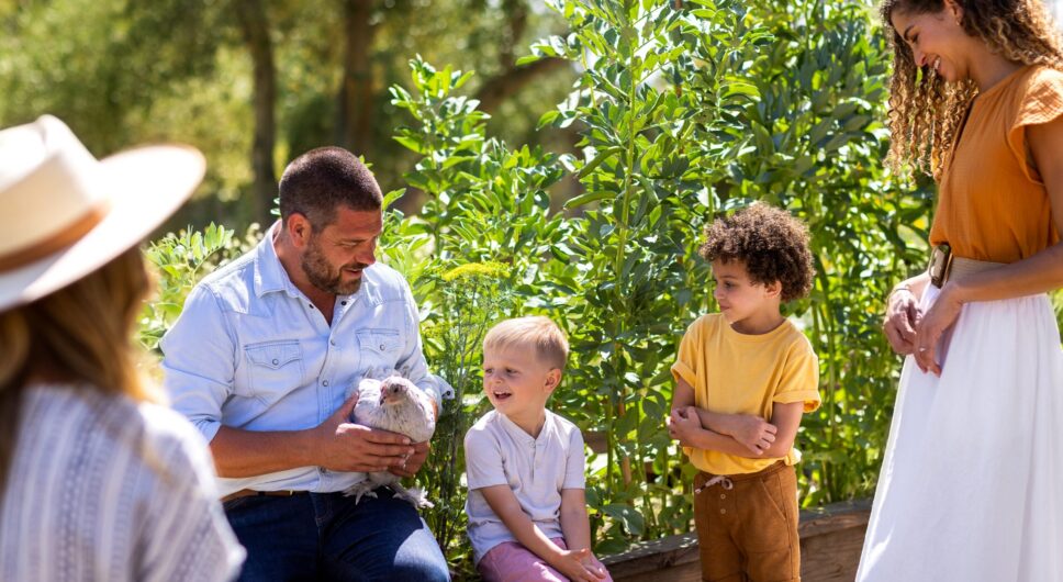 Man holding chicken with mothers and their sons