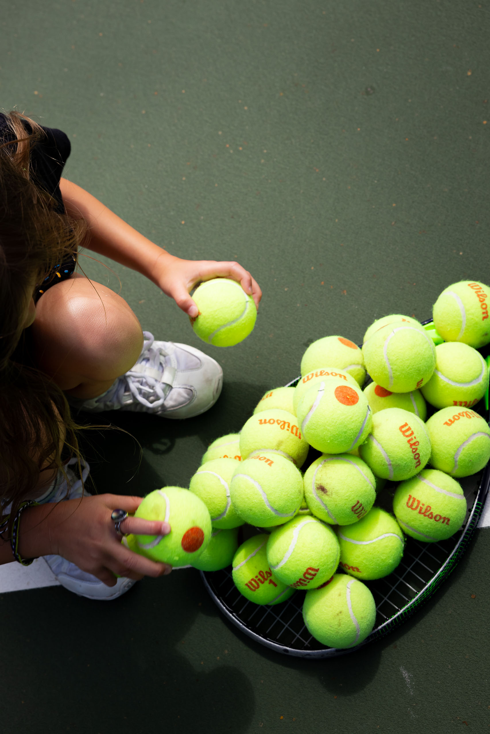 girl collecting tennis balls