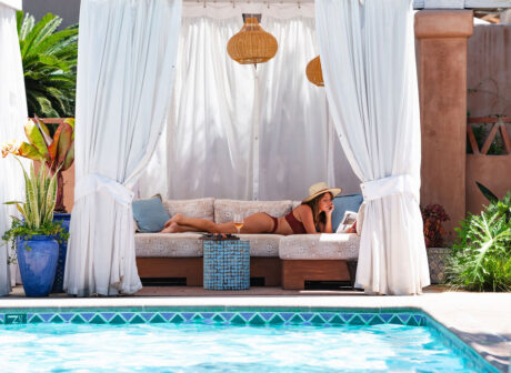 Woman lounging in a cabana reading a book.