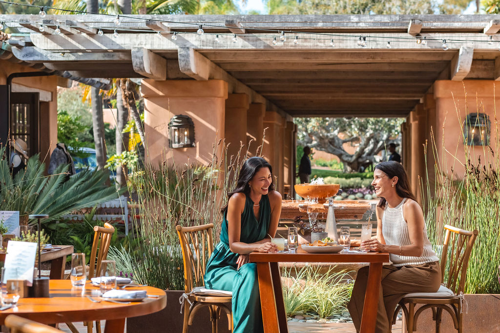 two women laughing having lunch on courtyard patio